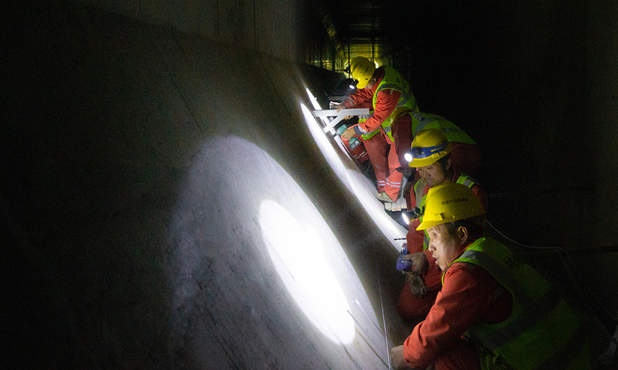 穿黃隧道工程裝飾裝修工程分為隧道暗埋段、隧道盾構段。盾構段采用超大斷面盾構法施工，盾構管片外徑為15.2米，管片內徑13.9米，由中國鐵建所屬中鐵十四局電氣化公司承擔全部裝飾裝修施工任務。圖為隧道內的施工工人。（范成濤 攝）