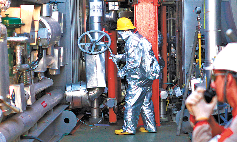 要通過熱采進行稠油開發，平臺生產區密布著蒸汽吞吐作業涉及的247臺設備，設備數量、規模、維保檢修的工作量絲毫不亞于一個中心平臺，生產現場管線密布錯綜，穿梭其中如置身鋼鐵叢林。開始注熱前的調試準備工作，讓秦斌和同事們忙得腳打后腦勺。最多的一天，秦斌一早簽了28份工單，在高峰作業期間，支持船和平臺作業人員有500余人。圖為身著防高溫防護服的操作員正在進行注熱開閥作業。