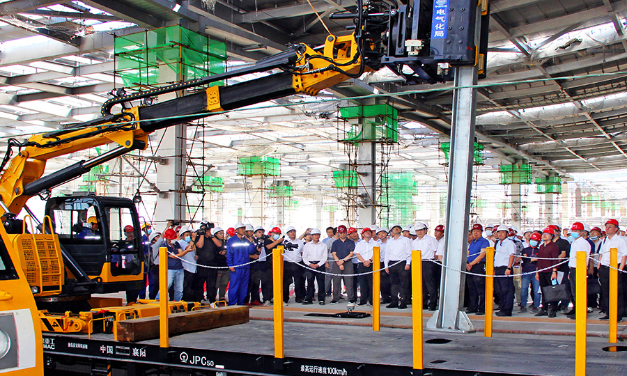 近日，在中國鐵建電氣化局京雄城際鐵路雄安站建設工地，我國自主研發的第一款接觸網三型智能化裝備投入使用。圖為在京雄城際雄安站站臺，國鐵集團調研組一行近距離觀摩接觸網立柱組立智能裝備作業情況。（侯欠欠 攝）