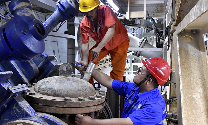 2020年4月份以來，盾構機從掘進460環開始出現震動、異響，經巡視和分析發現，竟然有一些石塊“躲”過了盾構機前端破碎機的“嘴巴”，流入出槳管道，卡死泥漿泵。這些石塊質地堅硬，鈣質結核，強度為45兆帕，相當于高鐵橋墩混凝土的強度，最大的一塊有75厘米長，重達150斤，他們果斷采取在泥漿管前加采石箱的方法將石頭阻擋在泥漿泵前面。圖為盾構機維保人員對盾構機上加裝的采石箱進行檢查。