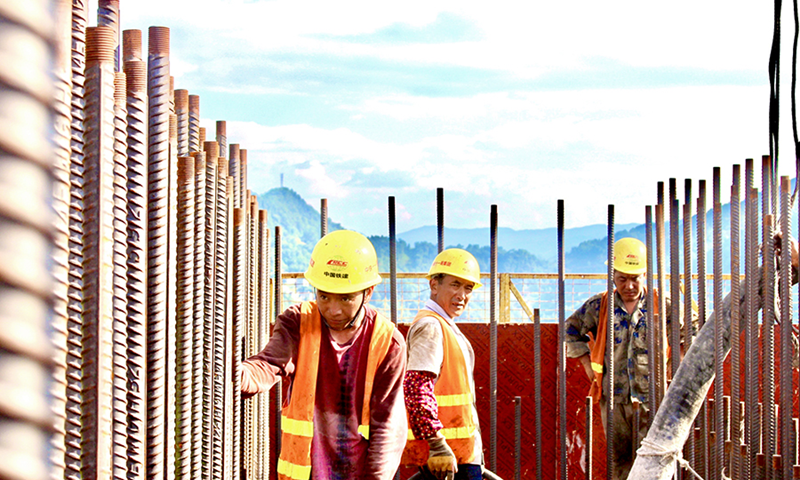 為全力做好迎峰度夏工作，位于重慶的中國鐵建所屬中鐵十一局承建的黔江繞城過境高速項目制定了多項夏季施工防暑“涼策”，為施工一線撐起“遮陽傘”。圖為烈日下的一線工人在百米墩身頂部進行混凝土澆筑作業。（馬奇 攝）