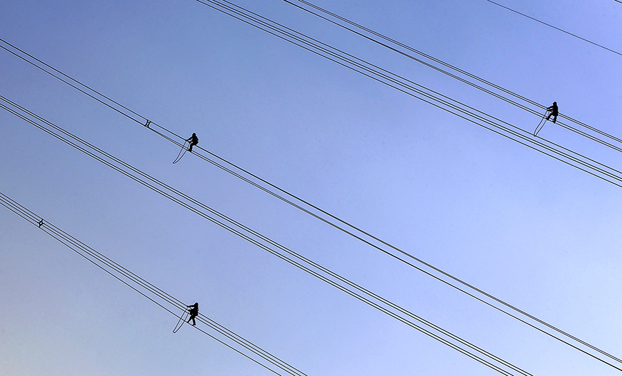 橫跨高速公路的50條高壓線，成為最大的“攔路虎”。特別是4條500千伏超高壓線路，每年只有一次停電遷改機會，成敗成為全線施工矚目的焦點。圖為高空中正在進行電力監測的工人。（范成濤 攝）