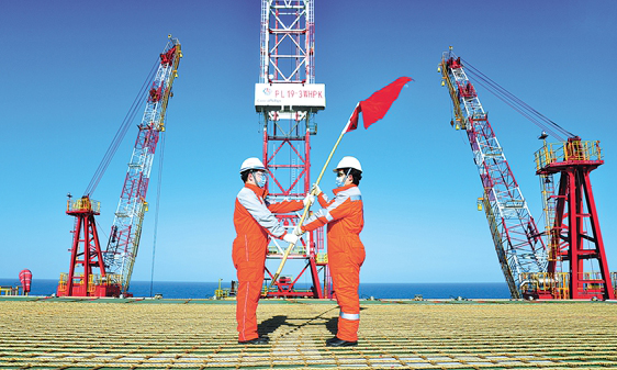 2月15日清晨，結束14天集中醫學觀察的上百名施工人員踏雪出征，拉開了項目復工復產序幕。這是一支堪比“紅旗半卷出轅門”的急行軍，剛剛抵達項目所在海域就投入到戰斗中。八個樁腿過渡段、2570噸的平臺東組塊、2450噸西組塊、1010噸生活樓、1190噸鉆井支持模塊、960噸的鉆井設備模塊……這些被“海上大力士”當空舞動的龐大身影，與波譎云詭的海況、凍穿棉衣的朔風，定格成一個個“我為祖國獻石油”的獨特勞動背景。圖為黨員突擊隊在平臺舉行授旗儀式。