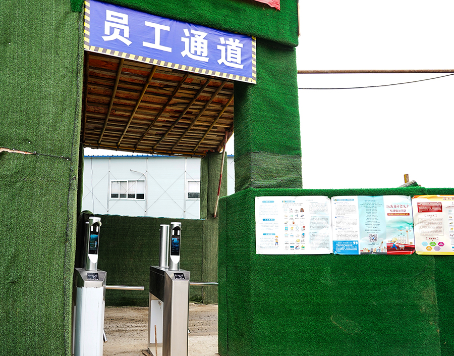 “攔住”張師傅的是中國鐵建所屬中鐵二十五局二公司南京仙林智谷項目部防疫檢測口新配備的刷臉設備。“當大家戴著口罩進入工區、項目部入口時，無須摘下口罩，和往常一樣刷臉就能通過門禁。”據介紹，這個設備可對佩戴口罩后的人臉進行準確識別，驗證成功后,自動發出信號打開門禁或閘機，記錄考勤信息；對未佩戴口罩或口罩佩戴不規范人員，拒絕通過，并報警提示值班人員。圖為值守在員工通道上的人臉識別系統。（王云海 攝） 