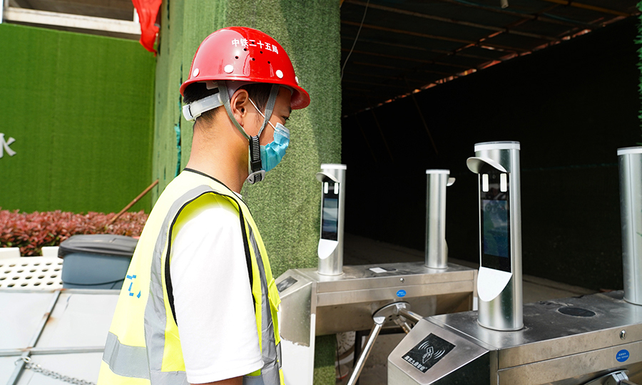 “嘀……認證失敗，無法通過!”“我戴了口罩呀，咋就過不去了呢？”剛剛下班的工人張師傅，對著門禁機試了好幾次，可就是過不去。值班人員見此情景，趕緊過來查看。“張師傅，你口罩戴得不規范，鼻梁都露出來一大截兒了。”“嘿，這家伙挺靈的。”調整了口罩之后，張師傅終于順利過關。圖為作業人員“刷臉”上下班。（王云海 攝） 