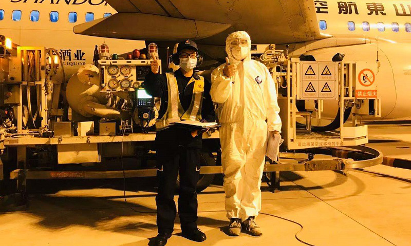 2月9日20時，武漢航空加油站飛機加油員正在保障馳援武漢的山東航空飛機供油。工作完成后，機組人員豎起大拇指，與飛機加油員合影，為武漢加油。（李菁 攝）