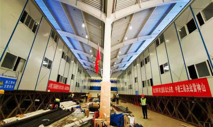 截至1月30日中午12時，雷神山醫院項目總體建設進度完成40％。隔離病房區場地平整、溝槽開挖、溝槽管線預埋、非溝槽區PE膜施工全部完成，溝槽回填已完成90％，條形基礎施工完成60％；集裝箱總計進場1518間，場外改裝完成約300套，現場已完成吊裝30間。醫護人員生活區A1－A7棟完成板房框架梁柱、樓面板、墻面板、屋面板等結構施工的70％。圖為醫護住宿區板房結構施工現場。