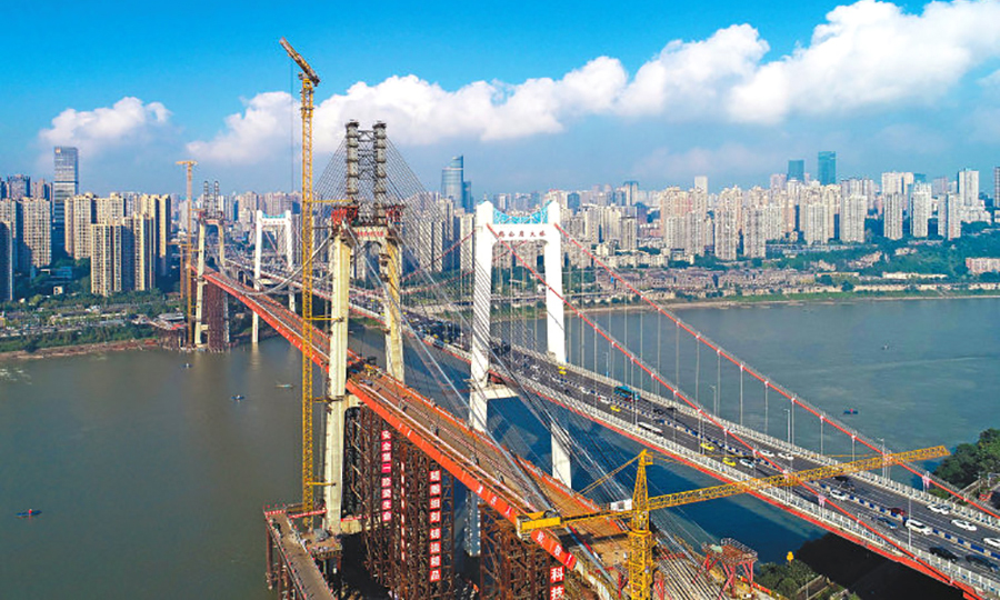 2019年12月30日，由中國鐵建投資集團投資的重慶軌道交通環線西南半環（海峽路～二郎段）正式開通試運營。該環線由中國鐵建所屬大橋局、中鐵十五局、中鐵十六局、中鐵十八局、中鐵二十三局、中鐵二十四局、中鐵建電氣化局參建。作為該項目的控制性工程，鵝公巖軌道專用橋主橋長1120米，引橋長530.5米，主跨為600米的雙塔雙索面五跨連續鋼箱梁自錨式懸索，跨徑為同類型橋梁世界之最。圖為鵝公巖軌道專用橋和老公路橋呈現的“姊妹橋”景觀。（趙冠喬 攝）