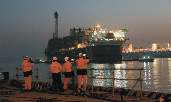 P70交付裝船現場，項目施工人員向即將駛向巴西的P70揮手道別。冬月的清晨，膠州灣海面瑞氣氤氳拂水來，當這座燈火通明的“鋼鐵巨城”倒映在海面上，遠處望去，它的燈光點亮了靜謐黑暗的夜空。