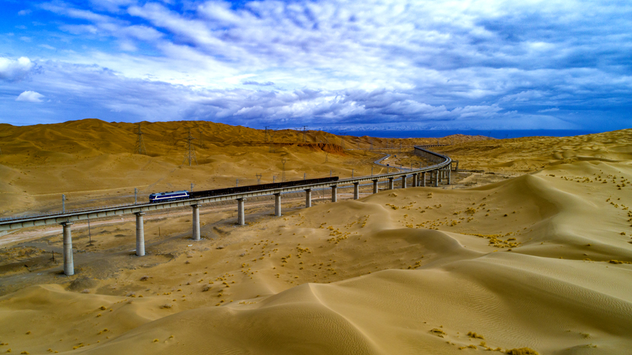 12月18日11時18分，一列火車緩緩開出格爾木站，標志著由中國鐵建所屬鐵一院勘察設計，中鐵十一局、中鐵十二局、中鐵十七局、中鐵十九局、中鐵二十一局和中鐵二十二局參建的敦格鐵路全線通車運營。圖為一列火車在沙山溝特大橋上通行。（金偉 攝）