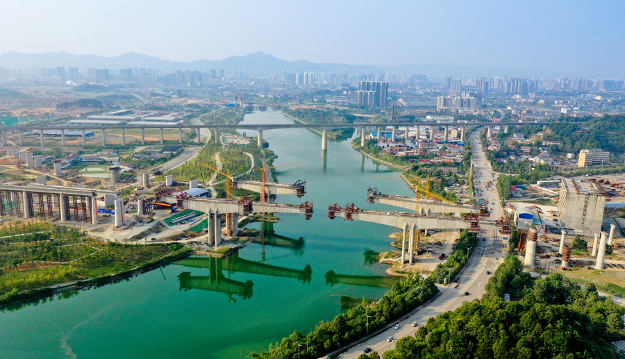 渝懷二線鐵路是國家中長期鐵路網規劃和國家鐵路“十二五”發展規劃的重要建設項目，承擔著武陵山區區域發展與扶貧攻堅的重任。由中國鐵建所屬中鐵二十五局承建的舞水灣特大橋是渝懷二線鐵路重難點工程，包含三座主跨168米的連續梁并列跨過舞水河，環水保要求高。項目部成立環水保專項工作組，通過掛籃兜底隔離防護、廢水三級沉淀處理等措施，用綠色施工呵護懷化市母親河及沿河風光帶。圖為施工中的舞水灣特大橋。