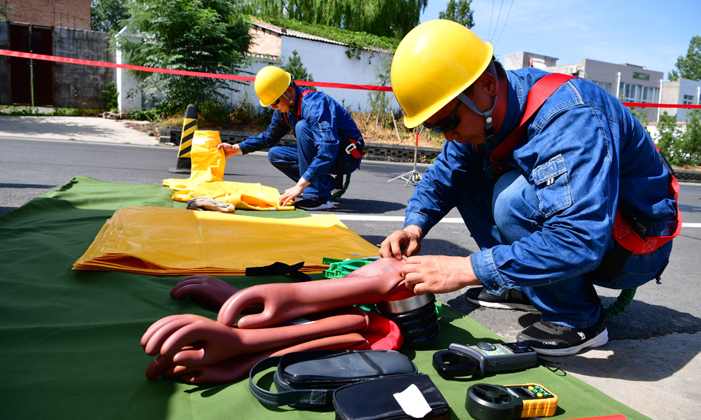今年46歲的尤寧是國家電網河南省新安縣供電公司帶電作業班的班長，1994年他從部隊轉業后成為一名電力工人。尤寧說，過去不能帶電作業，只能斷電作業，經常是為了一戶檢修，就要停掉整條線路。2012年，尤寧通過努力考取了帶電作業證。2017年，新安縣供電公司篩選技術能手，采購全套特種設備，組建了6個人的帶電作業班。圖為7月30日，在河南省新安縣正村鎮上坡村，尤寧（左）和同事一起做帶電作業前的準備工作。（新華社記者 馮大鵬 攝）