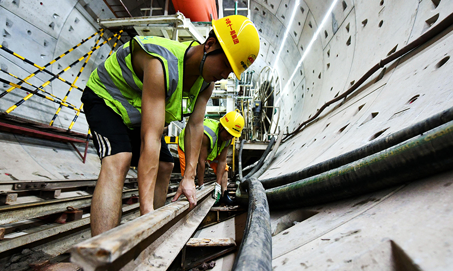 廣州地鐵18號線是全國在建時速最快的地鐵線路，全長約61公里，設計最高時速達160公里。項目建成后，從廣州南沙到廣州東站只需約30分鐘。圖為兩名工人正在轉移盾構電瓶車尾部軌道。