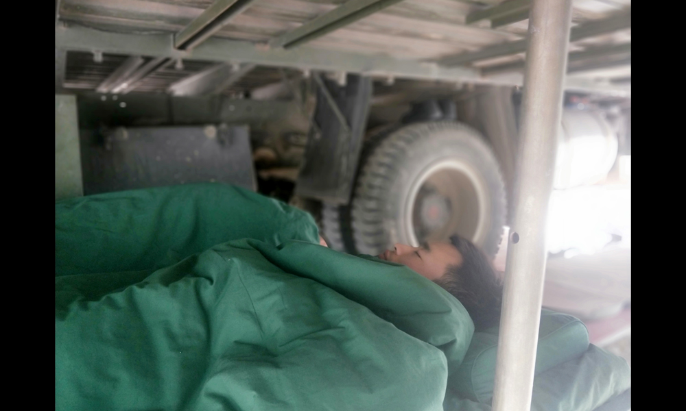 目前，中國安能第三工程局工作人員已奮戰多日，他們不僅晝夜施工，每天二十四小時兩班倒，還要在山里與烈日、冰雨和風沙抗爭，與蚊蟲戰斗。他們不怕吃苦、不畏艱難，用實際行動展現了央企的戰斗精神和過硬作風。圖為6月21日，由于天氣炎熱，夜班人員倒班回來在車底下休息。