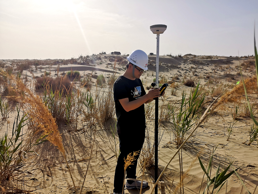 為確保安全優質高效地完成建設任務，中鐵十四局調集具有沙漠施工經驗的管理和施工人員，借鑒額哈鐵路建設經驗，成立課題攻關小組。全體建設者頂著漫天風沙在高達45攝氏度的環境中，僅用21天就完成了征地手續、電力引入、水源選取和便道拉通等工作，為加快和若鐵路建設打下堅實基礎。圖為中鐵十四局和若鐵路員工在塔克拉瑪干沙漠里進行測量工作。