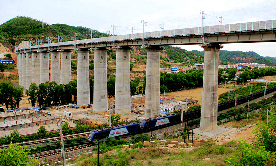 蒙華鐵路是世界上一次性建成最長的重載鐵路。線路跨越蒙、陜、晉、豫、鄂、湘、贛7省區，全長1837公里。該鐵路建成后，將成為我國“北煤南運”戰略運輸大通道，規劃年輸送能力超過2億噸。圖為蒙華鐵路蒙陜段第一高橋完工后火車下穿該橋。（許崗 攝）