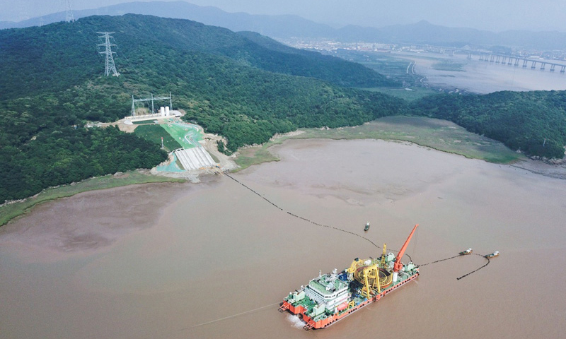 6月2日，舟山500千伏交聯聚乙烯海纜敷設工程順利完工。該工程分為兩回路，每回路敷設3根500千伏交聯聚乙烯海纜，從寧波市鎮海新泓口圍堤入海至舟山大鵬山島登陸，每條長16.8公里。500千伏交聯聚乙烯海纜在研發、實驗、檢測、制造上實現全程國產，促進了高端電纜國產化。圖為6月2日，最后一段海底電纜從海纜施工船上緩緩拖向舟山大鵬山島的終端站。（新華社記者 徐昱 攝）