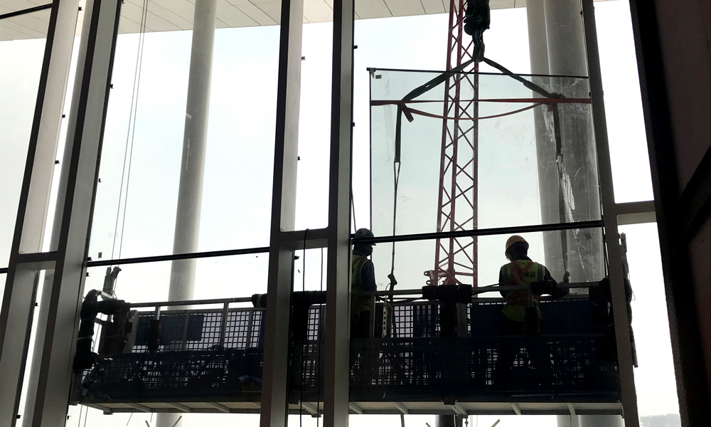 4月13日，西安絲路國際會議中心最后幾塊玻璃幕墻即將吊裝完畢，整個建筑的外立面將呈現完整效果。圖為4月13日，中建裝飾建筑工人正在吊裝FS1大跨度組合鋼吊柱玻璃幕墻。（國務院國資委網站 李子紅 攝）