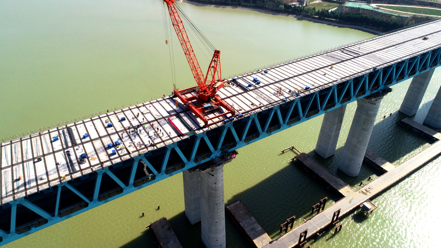 為克服高空作業、橋面板運輸困難、起吊噸位大、施工周期長等不利因素，施工團隊多次召開技術培訓交底會，在鋼桁梁南北兩端分別配備一臺70噸全回轉吊機進行架設施工，安排專人進行現場實時監管，確保安全、質量、進度全面可控。圖為三門峽黃河公鐵兩用大橋公路橋面板架設遠景。