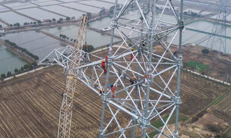 皖電東送特高壓重點改接工程從1月底將一直延續到2月中旬，為減少線路停電對居民生活和工業生產影響，施工人員利用春節期間工業用電低谷期組織停電改造施工。圖為2月1日，施工人員正在新建鐵塔上進行施工作業。（新華社記者 徐昱 攝）
