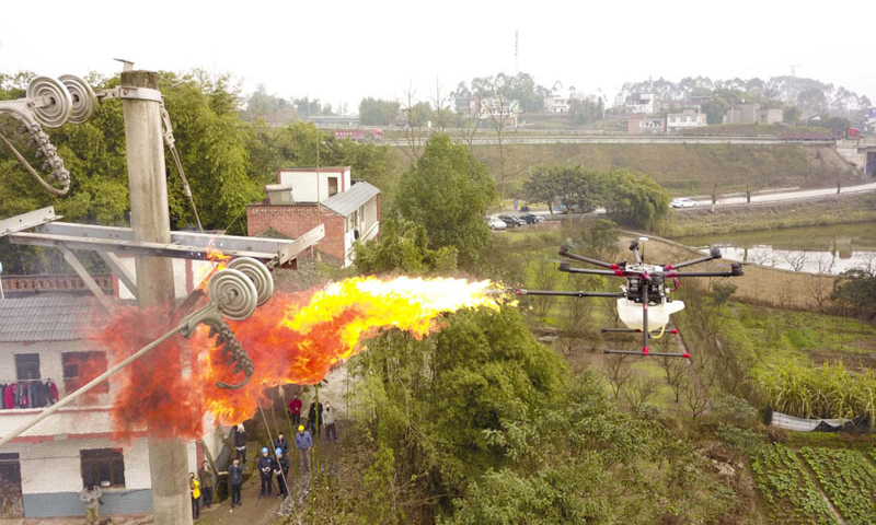 圖為1月16日，噴火清障無人機在國網重慶永川供電公司無人機班操作手的控制下，對重慶市永川區大安街道小坎村10千伏隆安線16號桿處的一個馬蜂窩進行噴火清除。（新華社記者 劉潺 攝）