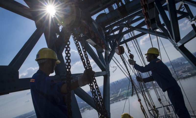 6月25日，工人們在南岸架設主纜。（新華社記者 肖藝九 攝）