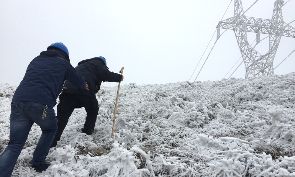 圖為南方電網云南公司昭通供電局近60歲的老員工帶著90后徒弟艱難的上山巡線中。（李建 攝）