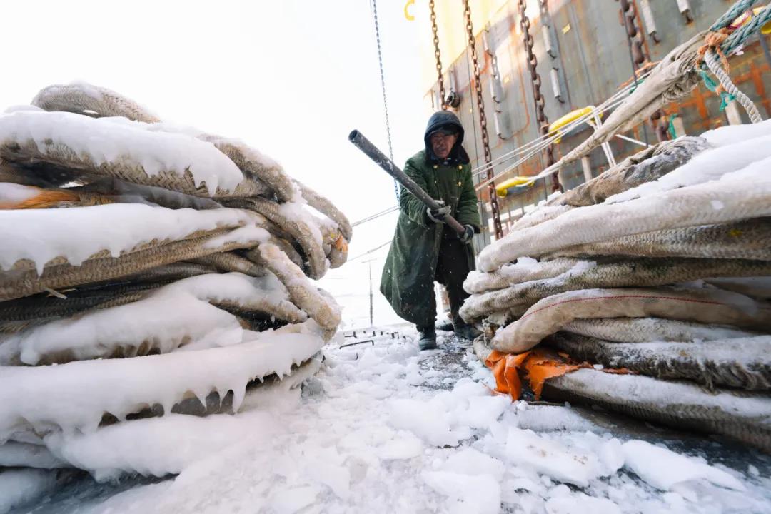 纜繩剛一出水就凍成了冰凌，一名工人舉著長長的十字鎬，用力敲打纜繩上的冰錐。