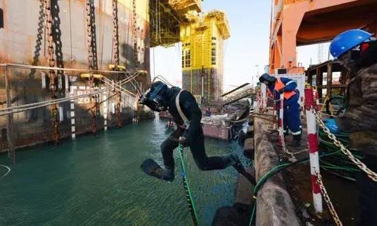 出發前一天，拖航工作組的謝維維、劉克建、許定創在平臺就位。姬曉東拿著對講機在平臺跑上跑下——啟航前，全平臺24個子系統的調試工作讓他一刻都無法停下腳步。中控室里，三名隨航值班人員緊盯屏幕，啟航前的最后準備階段，安全重于泰山。圖為“蛙人”為平臺水下設備做防護網固定工作。