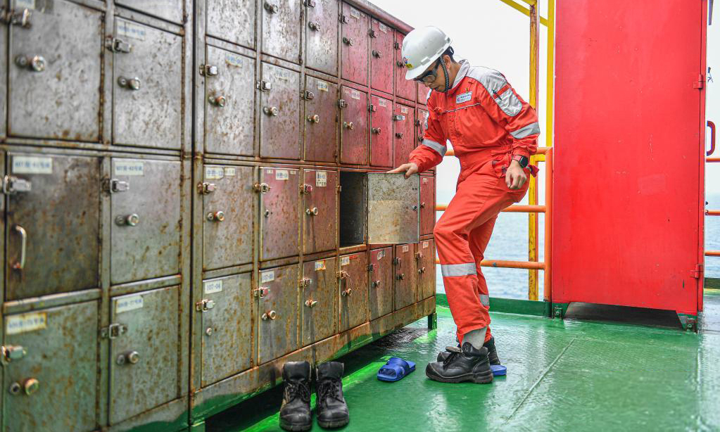 圖為4月25日，中國海油樂東15-1氣田上的一名工人在進入氣田作業區之前戴上安全帽并換上有助于保護腳部的工作靴。（新華社記者 蒲曉旭 攝）