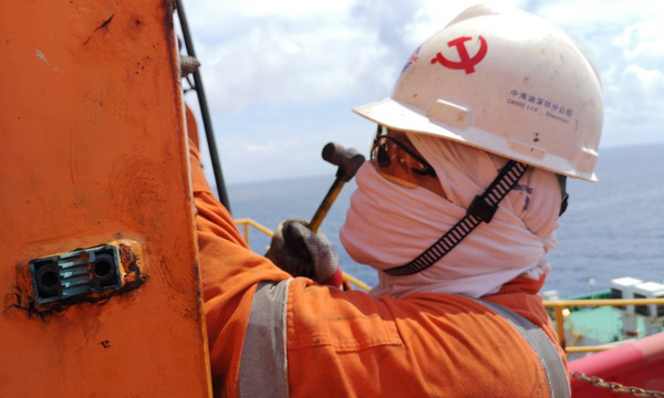 近日，有限公司深圳分公司恩平油田作業區“海洋石油 118”FPSO 的維修人員面對高溫天氣全副武裝防止中暑。圖為一名機械人員在奮力拆卸剎車皮銷軸。