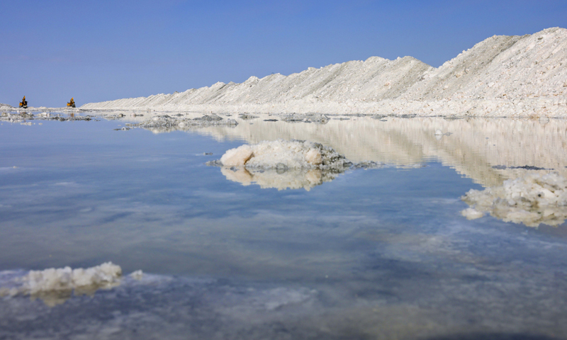 新疆和布克賽爾蒙古自治縣瑪納斯鹽湖擁有豐富的鹽礦資源，是重要的鹽業生產基地。近年來，當地企業通過持續改進工藝、開發特色鹽產品，銷售市場已從新疆拓展至國內其他省市。圖為6月21日，中鹽宏達鹽業的工人在新疆和布克賽爾蒙古自治縣瑪納斯鹽湖中采鹽。（新華社記者 胡虎虎 攝）