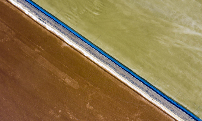 每年四月至十月是瑪納斯鹽湖的采鹽旺季，湖區內機器轟鳴、車輛穿梭，一片繁忙景象。圖為6月21日，在新疆和布克賽爾蒙古自治縣瑪納斯鹽湖中鹽宏達鹽業生產基地拍攝的一處灘曬池。（新華社記者 胡虎虎 攝）