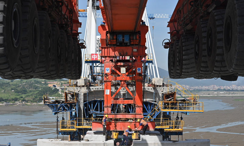 圖為7月11日，在新建福廈鐵路湄洲灣跨海大橋建設現場，中鐵十一局工人協同“昆侖號”千噸級運架一體機架設該線路最后一孔40米箱梁。（新華社記者 宋為偉 攝）