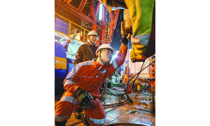 圖為鉆井監督雨中檢查出井鉆頭。