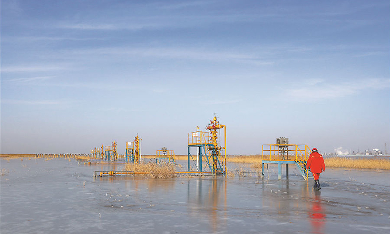 大港油田大張坨儲氣庫地處獨流減河泄洪區內。受上游泄洪影響，進站道路和部分采氣井被水淹沒，入冬后水面遇冷結冰。大張坨儲氣庫承擔著京津冀地區天然氣保供任務，干部員工不畏嚴寒，堅守保供一線，加密巡檢，嚴查隱患并及時整改，保障生產平穩運行。截至2021年12月31日，儲氣庫2021年已有12口井投入采氣生產，累計實現連續安全生產7722天。圖為大港油田員工踏冰巡檢。