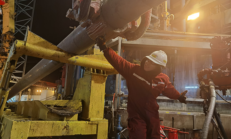 夜晚的鉆臺上，風雪突襲，氣溫接近零下20℃。為保障開發項目安全高效推進，平臺啟動關鍵崗位在崗機制，抓實現場安全管理，作業人員開足馬力全力奮戰下套管作業，助力稠油熱采早日投產。圖為套管作業人員卯足全力扣合吊卡，確保套管入井安全。