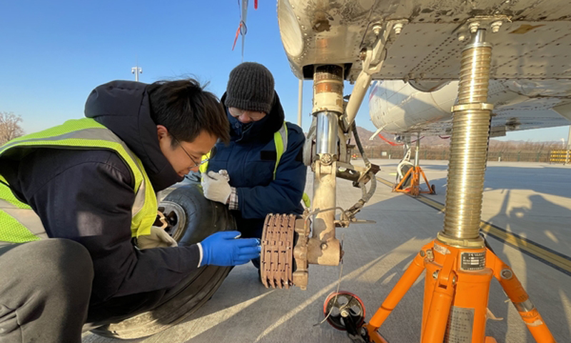 “全心全意備冬奧、一絲不茍保安全”，河北通航全體人員始終以奧運精神凝聚奮進力量，情系冰雪世界，營造優美壯觀的冬奧賽區雪景景觀，確保冬奧會保障任務順利圓滿完成。圖為機務人員維修飛機起落架和輪胎。（馮文佳　華玉兆　攝）