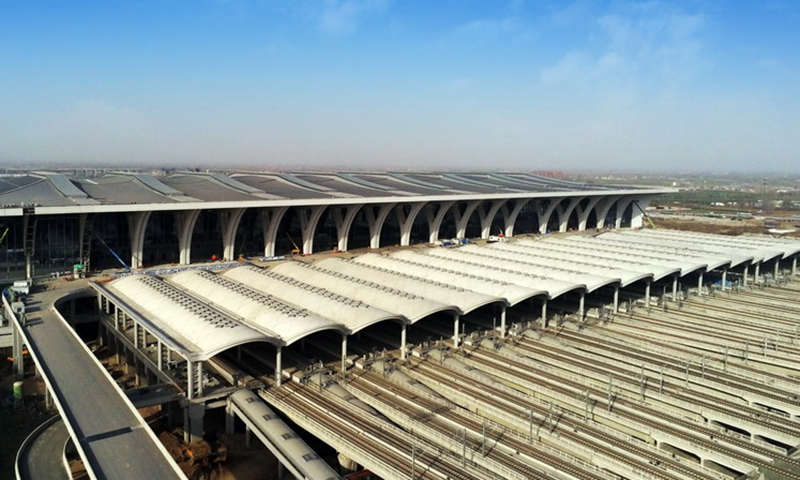 雨棚造型取自出土于河南的青銅器蓮鶴方壺中的仙鶴羽翼之形，屋蓋剖面形態為溫潤連貫的波浪，似仙鶴羽翼輕盈拍打，有“瑞鶴展翅”之意。據了解，為響應國鐵集團“綠色溫馨”的建設方針，雨棚整體建設采用了清水混凝土結構。這種混凝土一次澆筑成型，無需任何裝飾雕琢，且終生免維護，不僅綠色環保，還解決了運營期間設備維護與開放維護時間矛盾的難題。圖為外部雨棚成品側面。