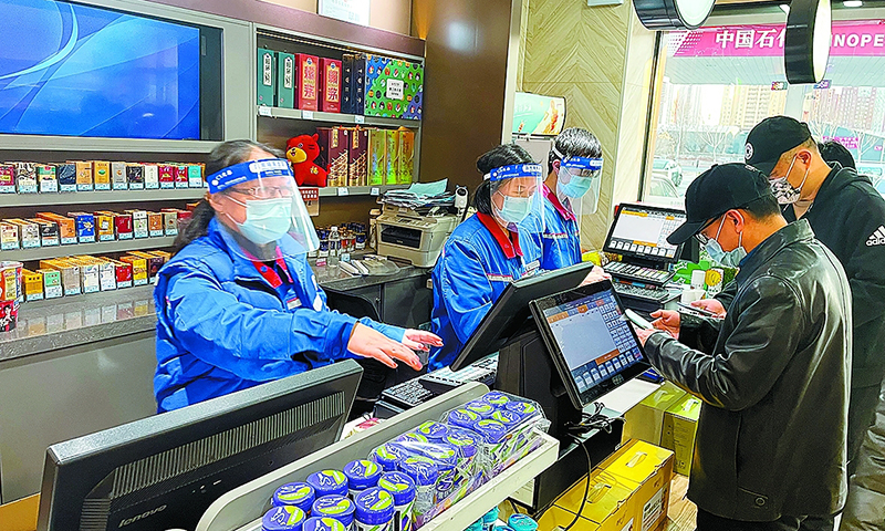 連日來，吉林、山東、廣東等地突發疫情，中國石化各企業全面進入應急狀態，嚴格落實防控措施，升級防疫物資配置，提前備足油品和民生商品，在保障員工生命健康安全、穩定市場供應的同時，組建志愿者突擊隊支援社區，齊心協力為疫情防控貢獻石化力量。圖為吉林長春石油惠工路加油站員工堅守崗位，為購買油品和生活物資的市民服務。（孫琬姝 攝  歐云瑞 文）  