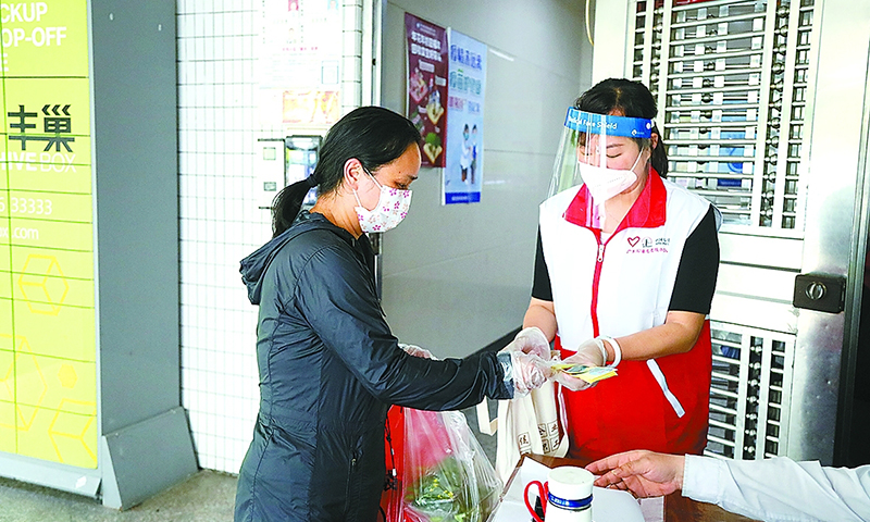 圖為深圳石油志愿者在國城花園社區開展志愿服務，為社區民居派發出入憑證。（劉科美 攝）