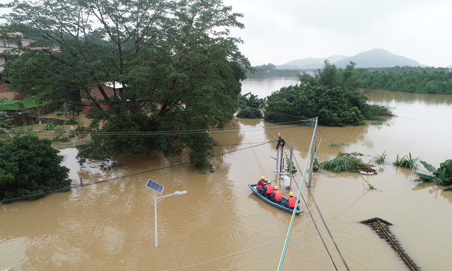 6月15日，隨著2022年“北江一號”洪水過境，廣東清城區源潭鎮轄區內大燕河水位不斷升高，導致源潭鎮老窯村部分房屋被洪水浸泡。南方電網廣東清遠清城供電局源潭供電所工作人員劃船前往村中了解居民受災情況，并檢查安全隱患采取緊急停電措施，保障村民們汛期用電安全。（覃軒-攝）