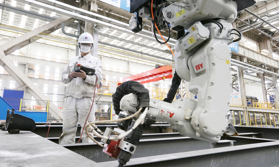 6月26日，中國海油對外宣布，我國首個海洋油氣裝備制造“智能工廠”——中國海油海油工程天津智能化制造基地正式投產，標志著我國海洋油氣裝備行業智能化轉型實現重大突破。圖為施工人員操作機器人進行鋼架構焊接作業。賈雪東 攝