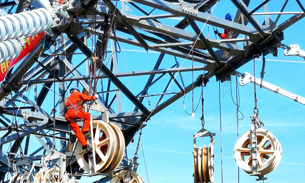 2022年8月20日，湖北省恩施土家族苗族自治州巴東縣東瀼口鎮綠竹筏村，電力工人冒著40℃以上的高溫跨越長江施工作業。張遠明 攝