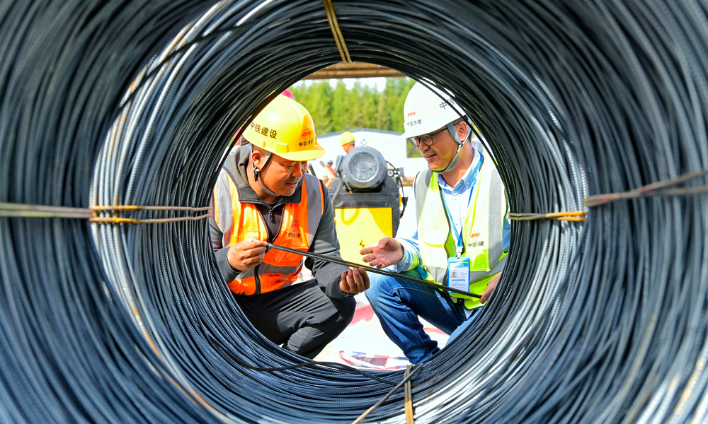 哈伊高鐵鐵伊段沿線分布多塊島狀凍土帶，伊春西站施工地點凍土層厚度達2.9米，凍脹敏感性大、穩定性差，給施工帶來極大難度。中鐵建設聯合哈爾濱工業大學科研團隊開展國內首個防凍害材料新技術課題研究，采用這種新技術對軟土實施固化密實加固，實現地基凍害防控。圖為建設者在施工現場進行討論。