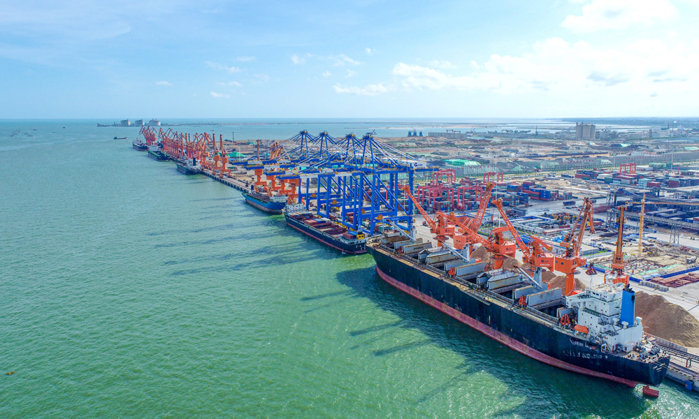 近日，北部灣港輪船進進出出，運輸車輛絡繹不絕，碼頭生產作業一派繁忙景象。門式抓斗起重機巨大的抓斗將銅精礦從滿載的船舶上卸下，由集裝箱卡車運至火車，一列列裝滿貨物的班列從碼頭奔向全國各地。