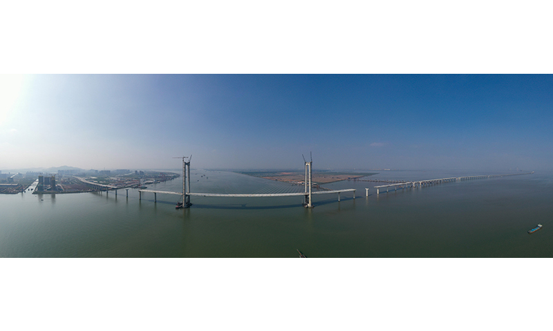 10月8日，隨著第155片60米混凝土箱梁在廣東中山智慧梁場完成預制，由中鐵大橋局承建的深中通道全線非通航孔橋共791片混凝土箱梁預制工作全部完成。深中通道是集“橋、島、隧、水下互通”于一體的超大型跨海集群工程，全長約24公里，其中橋梁工程長約17公里。圖為建設中的深中通道中山大橋。新華社記者 劉大偉 攝