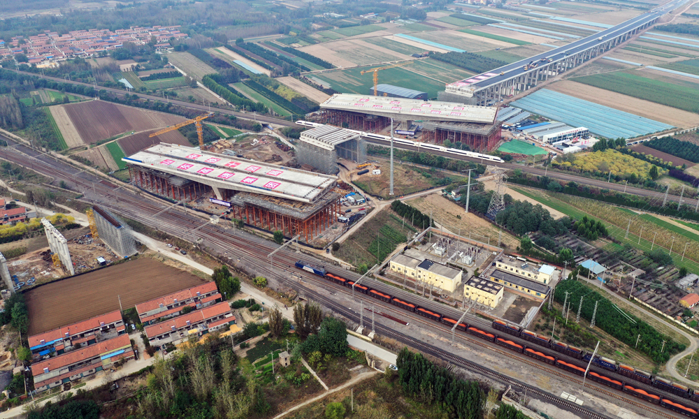 作為濰青高速的關鍵控制性工程，上跨橋分別與膠濟客專和膠濟鐵路2條線路連續交叉，采用T型剛構連續梁轉體施工，是國內目前總噸位最重、橋面最寬的高速公路跨鐵路連續T型剛構轉體橋。該工程主梁線形控制、技術精度要求極高，緊鄰膠濟客運專線和膠濟鐵路等繁忙干線，每天通過列車多達305趟。在轉體過程中，建設團隊首次使用北斗導航定位系統對橋梁轉角及姿態監控，實時采集數據，通過“全程可視化、控制智能化”提前分析告警，保障夜間施工安全可控。圖為鐵路列車經過轉體前的大橋旁。