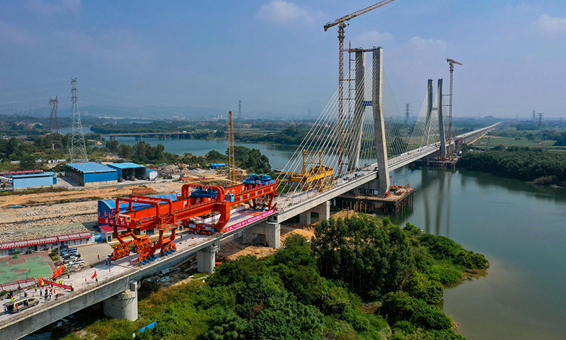 10月25日，中鐵五局承建的廣汕鐵路鋪架施工最后一孔900噸箱梁成功架設在廣州增江特大橋橋墩上，標志著全線箱梁架設完成。圖為施工人員操作架橋機將最后一孔900噸箱梁成功架設在增江特大橋橋墩上（無人機照片）。新華社記者 劉大偉 攝