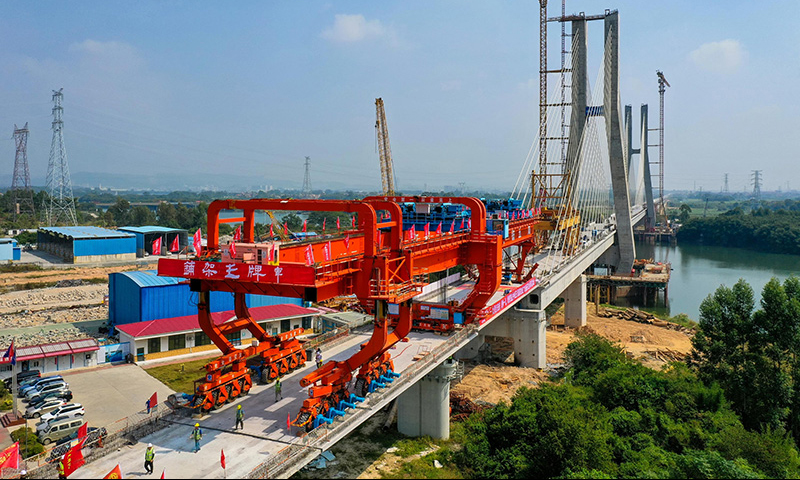 設計時速350公里的廣汕鐵路全長206.2公里，途經廣州、惠州、深汕合作區、汕尾，全線預計2023年建成通車。通車后，廣州到汕尾運行時間將由現在的2小時左右縮短至40分鐘左右，將有力助推粵東地區加快融入粵港澳大灣區。圖為10月25日，施工人員操作架橋機將最后一孔900噸箱梁成功架設在增江特大橋橋墩上（無人機照片）。新華社記者 劉大偉 攝